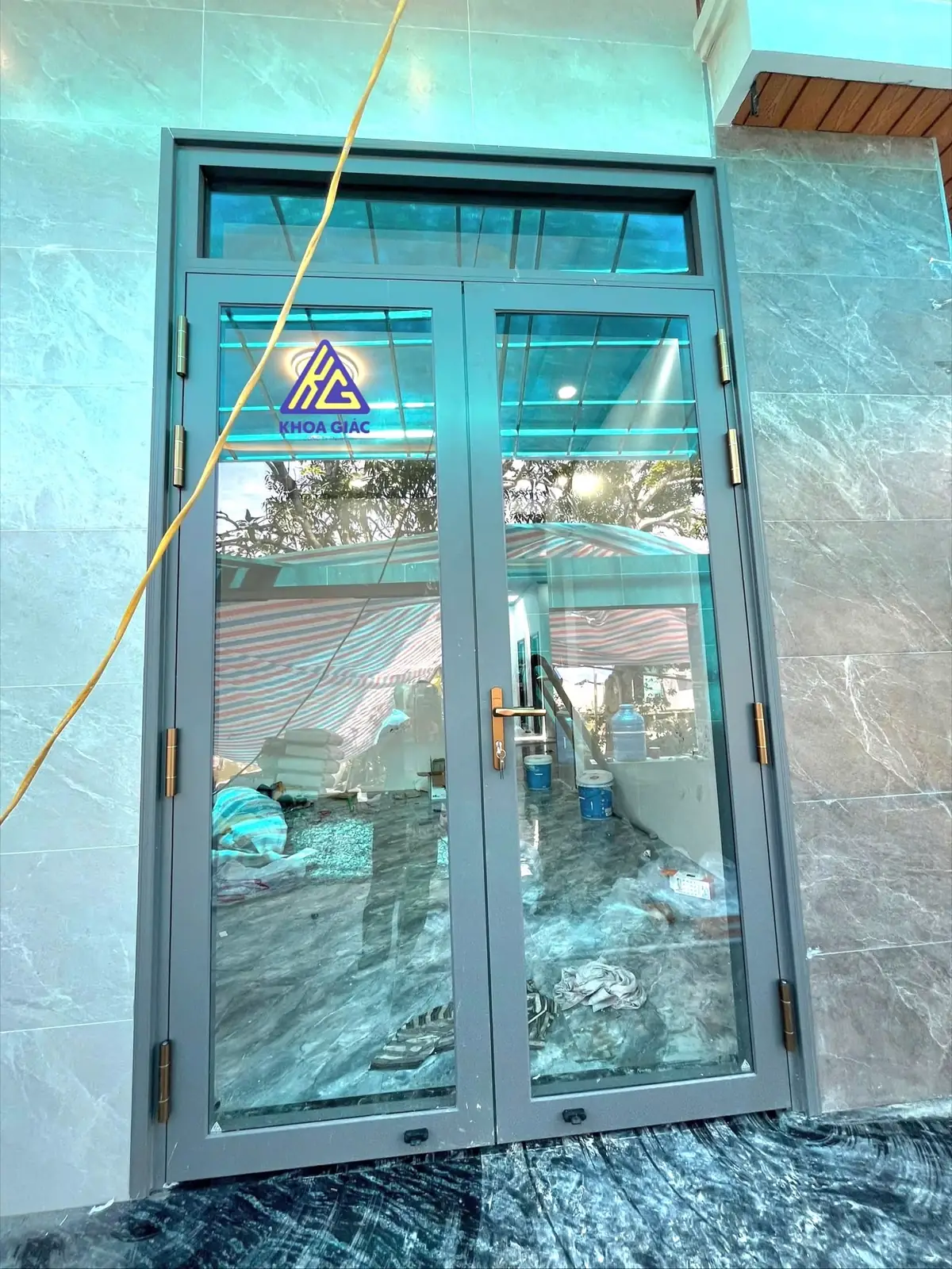 Cửa nhôm Xingfa 2 cánh mở quay màu ghi có ô kính trên, mặt tiền ốp đá
