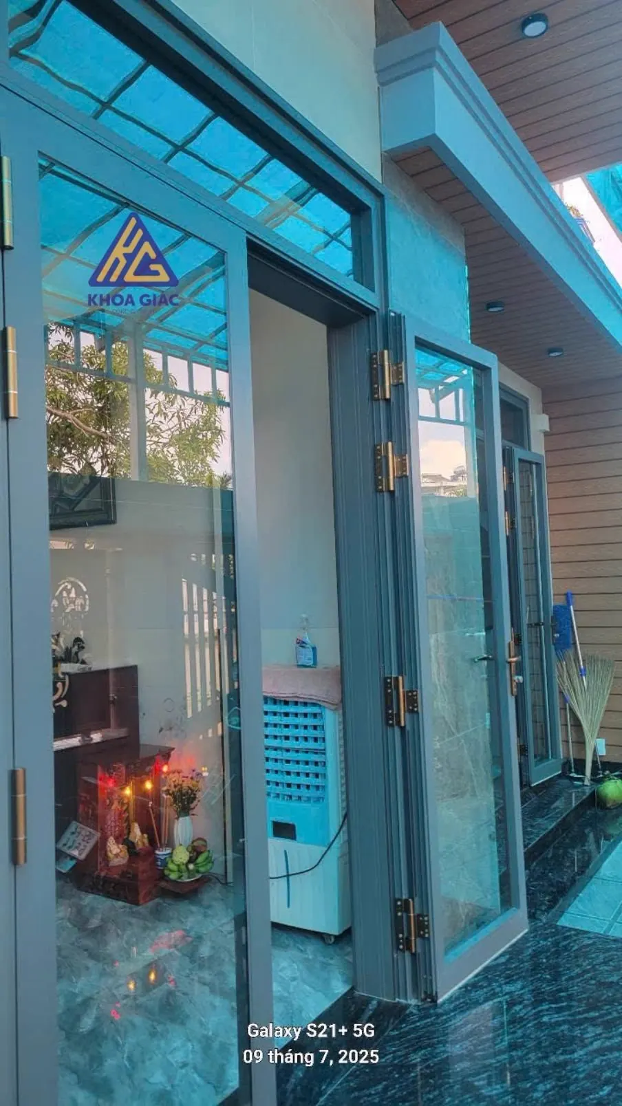 Cửa nhôm 2 cánh màu ghi mở ra hiên lát đá