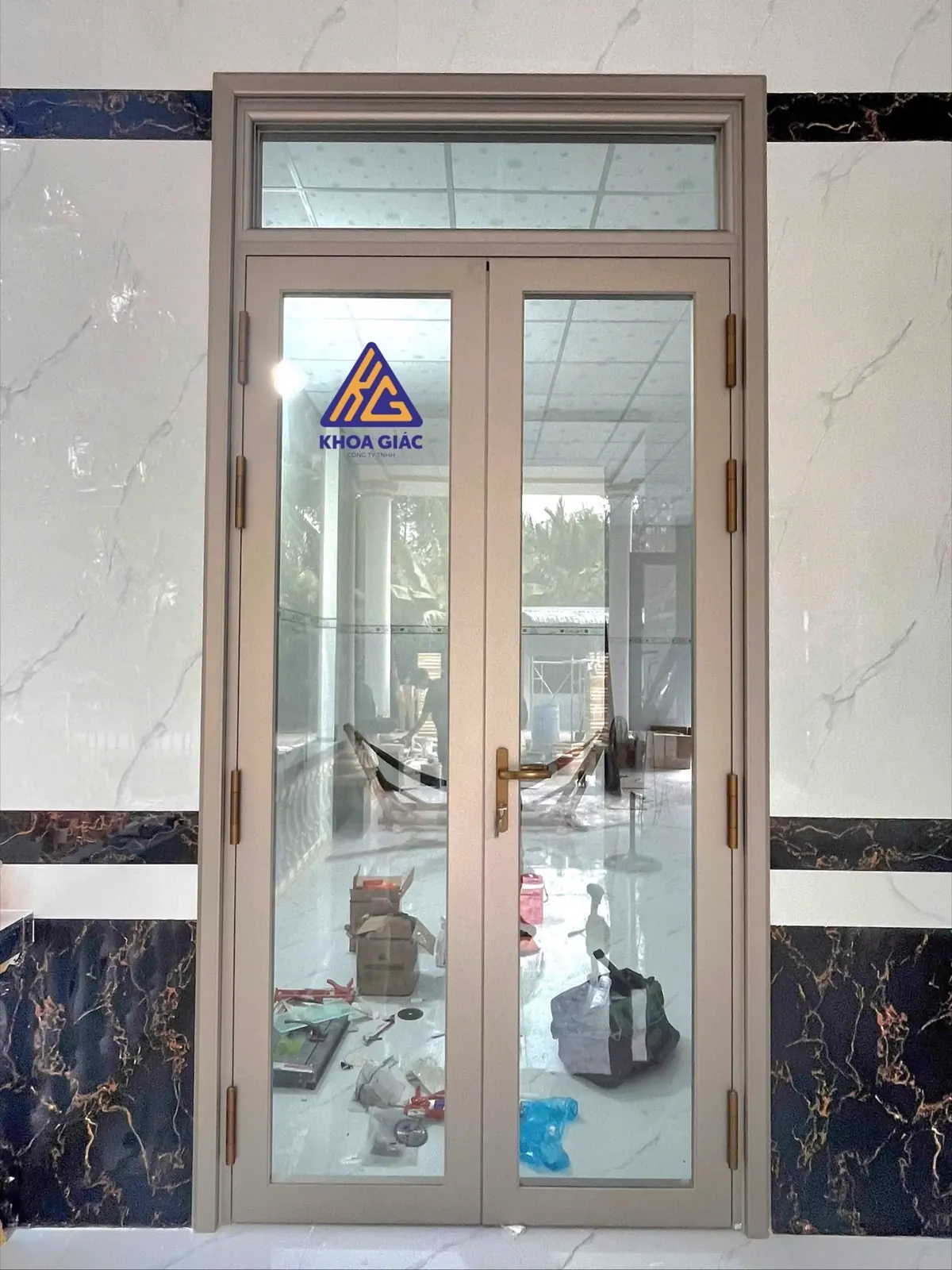 Cửa nhôm 2 cánh màu champagne có ô kính trên, tường ốp đá