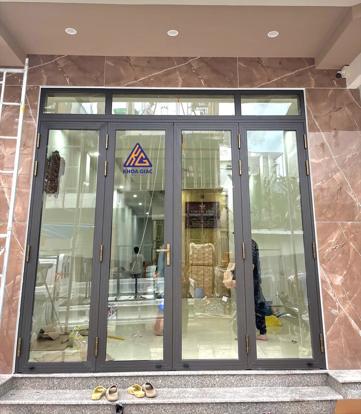 Cửa nhôm Xingfa 4 cánh mở quay màu ghi, ô kính trên, mặt tiền ốp đá